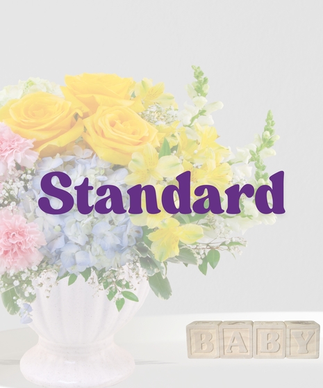 Heaven Sent flower arrangement with yellow roses, blue hydrangeas, pink carnations, and alstroemeria in a cream pedestal vase for a baby shower or gender-neutral gift