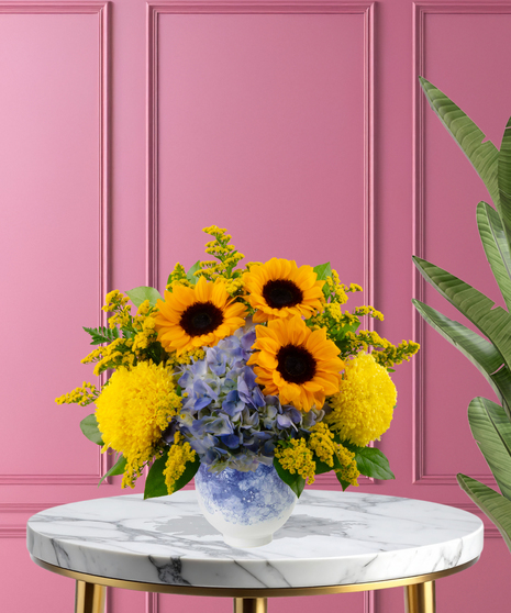 Hello Sunshine exclusive Valentine's Day friendship arrangement with sunflowers, yellow roses, and blue hydrangeas in a blue-and-white marbled vase.