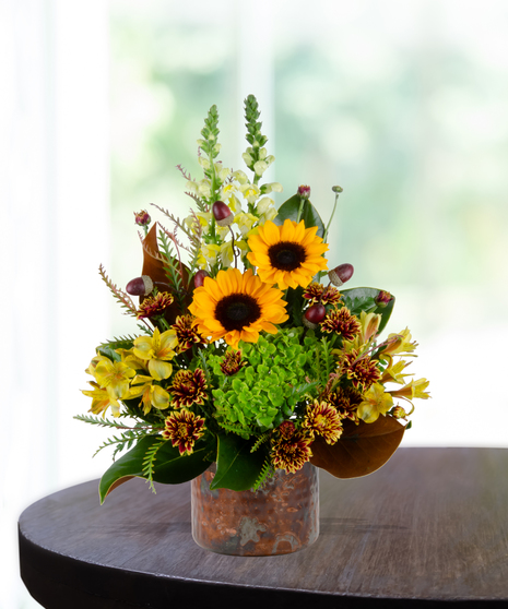 Maple Mood flower arrangement with sunflowers, yellow roses, bronze mums, and greenery in a copper vase.