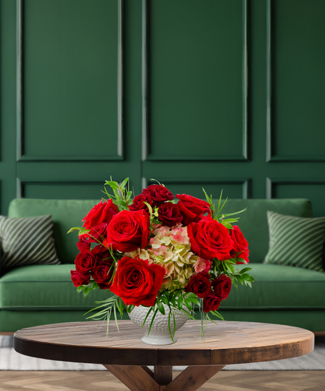 Ruby Reserve luxury Christmas flower arrangement with abundant deep red roses and green hydrangea accents in a textured white vase