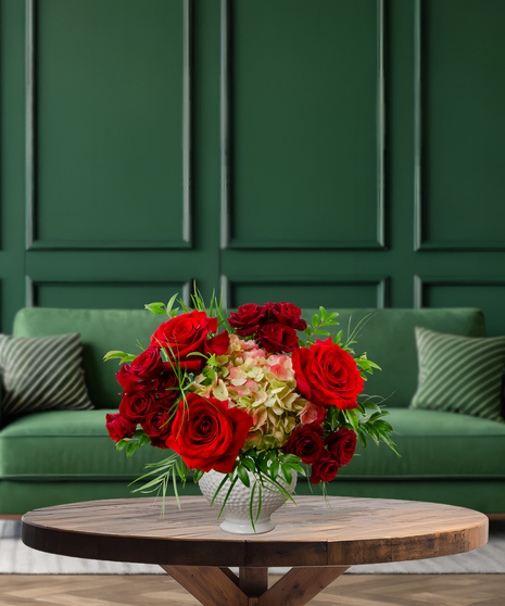 Ruby Reserve luxury Christmas flower arrangement with abundant deep red roses and green hydrangea accents in a textured white vase
