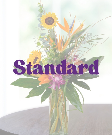 Kiely tropical flower arrangement with sunflowers, birds of paradise, orchids, lilies, and tropical greenery in a tall glass vase