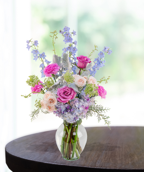 Lavender Haze flower arrangement with lilies, pink roses, blue hydrangeas, and delphinium in a lavender vase