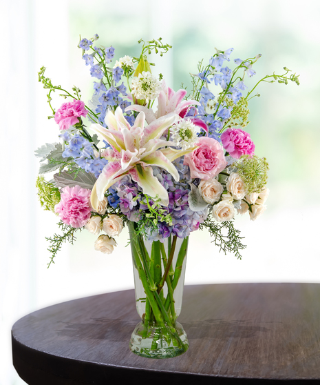 Lavender Haze flower arrangement with lilies, pink roses, blue hydrangeas, and delphinium in a lavender vase