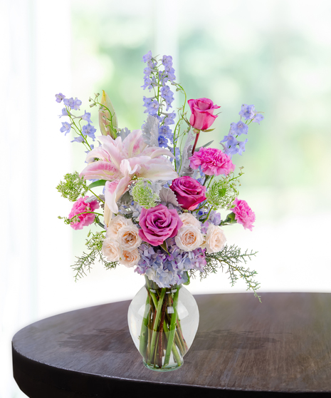 Lavender Haze flower arrangement with lilies, pink roses, blue hydrangeas, and delphinium in a lavender vase