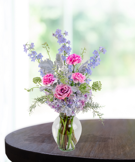 Lavender Haze flower arrangement with lilies, pink roses, blue hydrangeas, and delphinium in a lavender vase