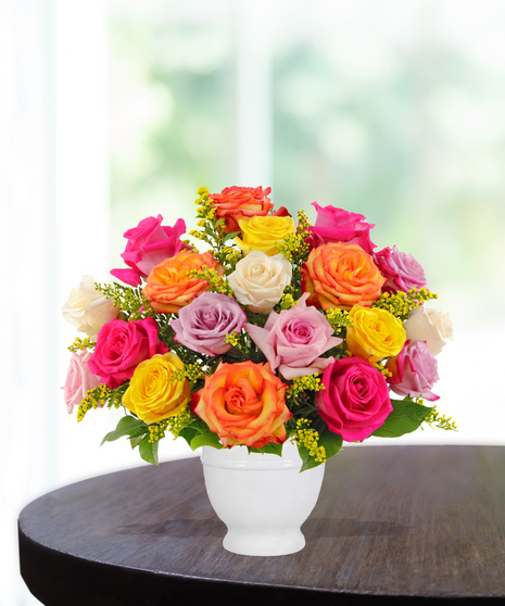Color Me Happy arrangement with vibrant roses in pink, yellow, lavender, orange, and cream in a white pedestal vase