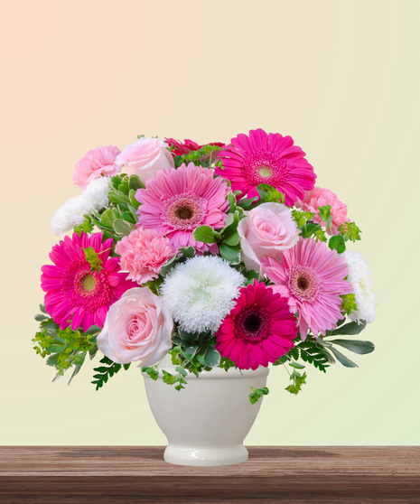 Love You Bunches floral arrangement with pink gerbera daisies, roses, carnations, and white mums in a white vase – cheerful bouquet for Mother’s Day.