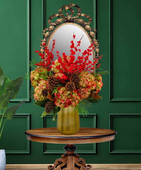 Lush Holiday arrangement with red Ilex berries, russet hydrangeas, and pinecones in a golden-green vase from Billy Heroman's.