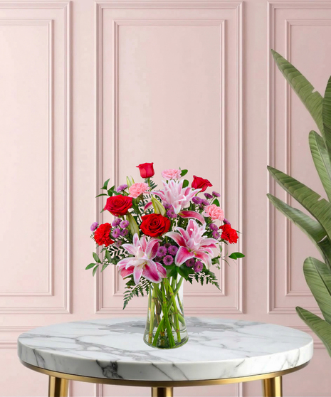 Open Arms Mother's Day flower arrangement featuring red roses, pink rose lilies, and more in a traditional glass vase.