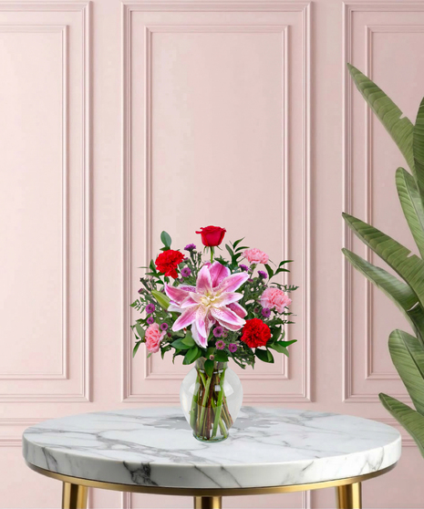 Open Arms Mother's Day flower arrangement featuring red roses, pink rose lilies, and more in a traditional glass vase.