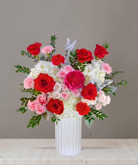 P.S. I Love You flower arrangement with red roses, pink garden roses, blush spray roses, and hydrangeas in a tall white vase