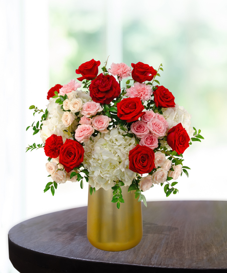 P.S. I Love You luxury Valentine's arrangement with red roses, red garden roses, white hydrangeas, and pink spray roses in a satin gold metallic vase.