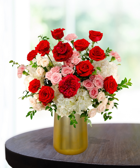 P.S. I Love You luxury Valentine's arrangement with red roses, red garden roses, white hydrangeas, and pink spray roses in a satin gold metallic vase.