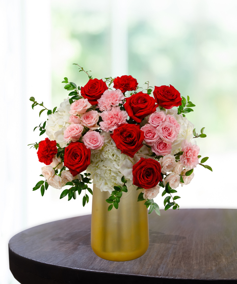 P.S. I Love You luxury Valentine's arrangement with red roses, red garden roses, white hydrangeas, and pink spray roses in a satin gold metallic vase.