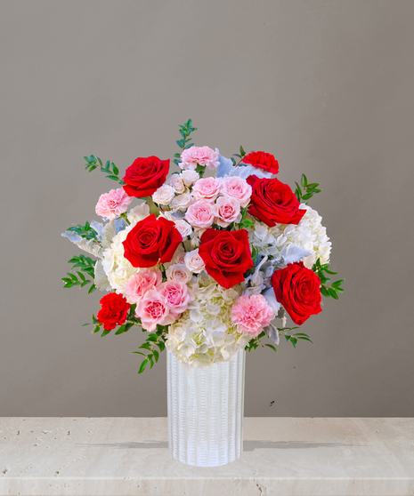 P.S. I Love You flower arrangement with red roses, pink garden roses, blush spray roses, and hydrangeas in a tall white vase