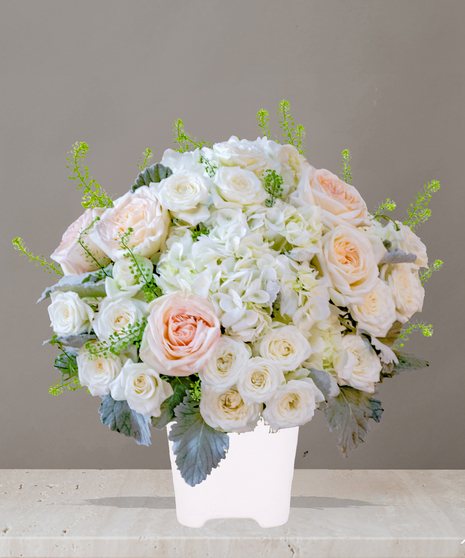 Billy Heroman's Signature Collection white and blush flower arrangement with roses, hydrangeas, and greenery in a textured white vase
