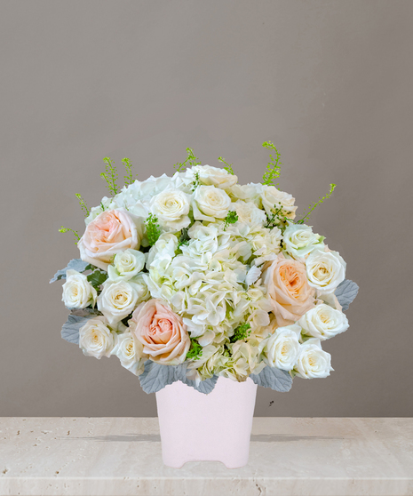 Billy Heroman's Signature Collection white and blush flower arrangement with roses, hydrangeas, and greenery in a textured white vase