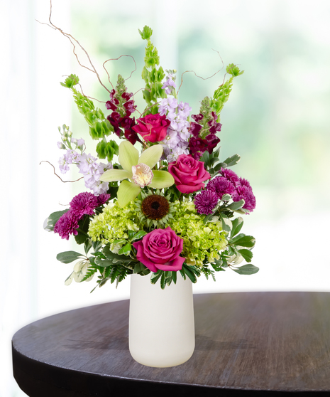 Green and purple birthday flower arrangement with orchids, roses, and hydrangeas