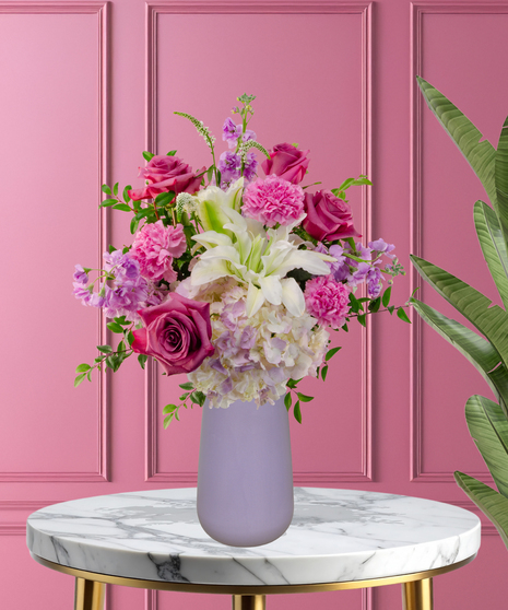 Pretty in Purple exclusive Valentine's and February birthday flower arrangement with lavender roses, white lilies, purple stock, and magenta mums in a frosted lavender vase.