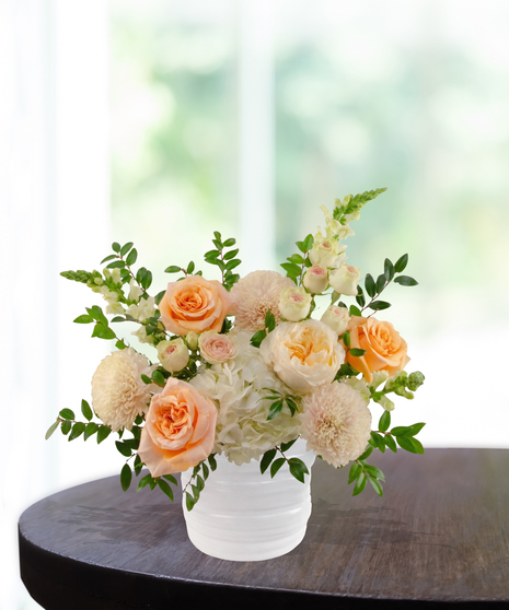 Just Peachy exclusive April birthday flower arrangement with peach garden roses, cream spray roses, white hydrangeas, and snapdragons in a ridged white vase.