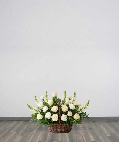 Purity Basket white sympathy flower arrangement featuring white roses, white carnations, white snapdragons, and lush green foliage in an 8-inch dark woven basket with a handle