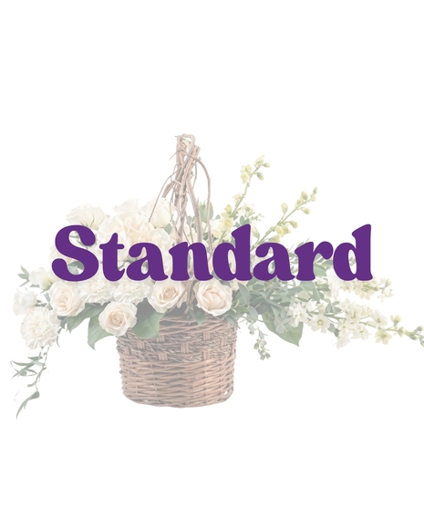 Purity Basket white sympathy flower arrangement featuring white roses, white carnations, white snapdragons, and lush green foliage in an 8-inch dark woven basket with a handle