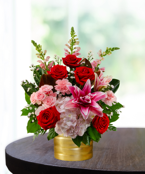 Queen of Hearts exclusive Valentine's flower arrangement with red roses, pink lilies, pink hydrangeas, pink snapdragons, and spray roses in a ribbed gold metallic vase.