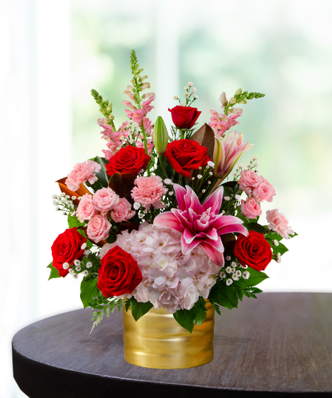 Queen of Hearts exclusive Valentine's flower arrangement with red roses, pink lilies, pink hydrangeas, pink snapdragons, and spray roses in a ribbed gold metallic vase.