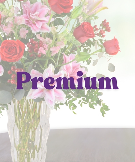 Romance Me anniversary bouquet with red roses, pink rose lilies, snapdragons, and red berries in a tall glass vase