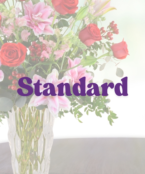 Romance Me anniversary bouquet with red roses, pink rose lilies, snapdragons, and red berries in a tall glass vase