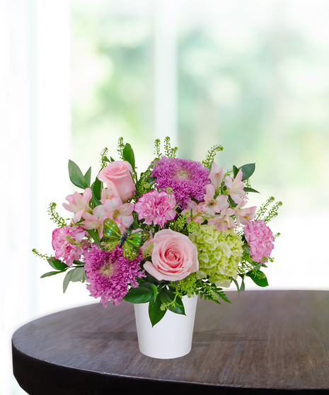 Rosy Posy flower arrangement with soft pink roses, pink carnations, alstroemeria, lavender mums, and green hydrangea in a white vase.