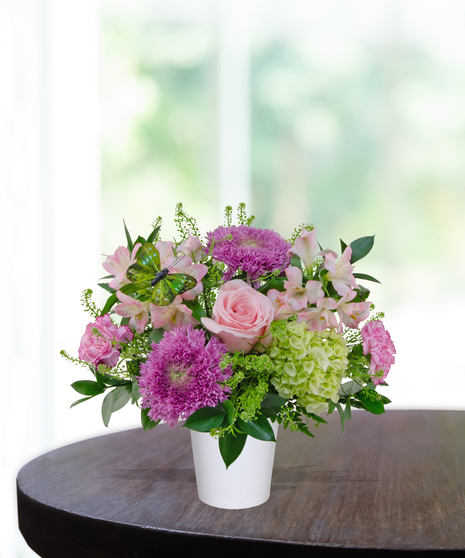 Rosy Posy flower arrangement with soft pink roses, pink carnations, alstroemeria, lavender mums, and green hydrangea in a white vase.