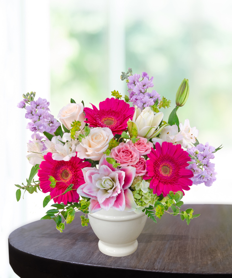 Pink Carats floral arrangement featuring pink roses, gerbera daisies, lilies, hydrangeas, and spring blooms in an ivory vase – an April birthday exclusive.