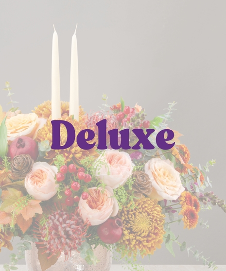 Sienna fall flower centerpiece with peach roses, gold mums, berries, pinecones, and candles in a textured vase