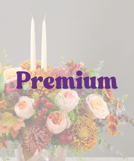 Sienna fall flower centerpiece with peach roses, gold mums, berries, pinecones, and candles in a textured vase
