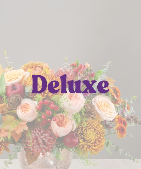Sienna fall flower centerpiece with peach roses, gold mums, berries, pinecones, and candles in a textured vase