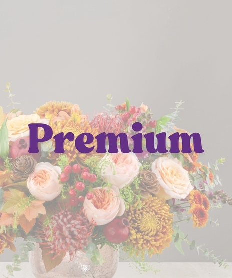 Sienna fall flower centerpiece with peach roses, gold mums, berries, pinecones, and candles in a textured vase