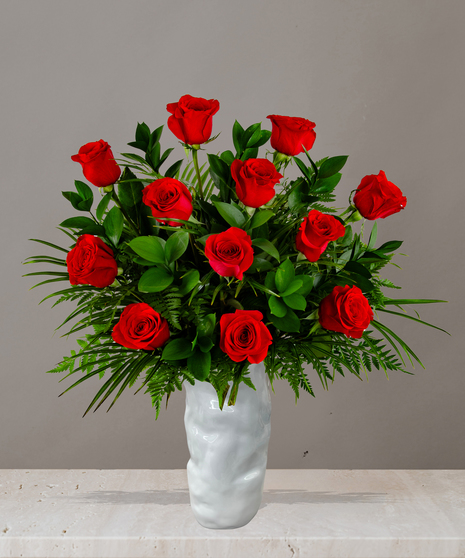 Rose arrangement from Billy Heroman’s with long-stemmed red roses in a white vase, available in one, two, or three dozen options with lush greenery.
