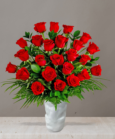Rose arrangement from Billy Heroman’s with long-stemmed red roses in a white vase, available in one, two, or three dozen options with lush greenery.