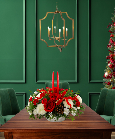 'Tis the Season classic Christmas centerpiece with red roses, white carnations, white mums, pine cones, evergreen, red ribbon, and two red candles in a textured white vase