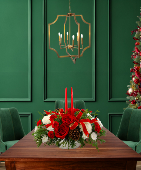 'Tis the Season classic Christmas centerpiece with red roses, white carnations, white mums, pine cones, evergreen, red ribbon, and two red candles in a textured white vase