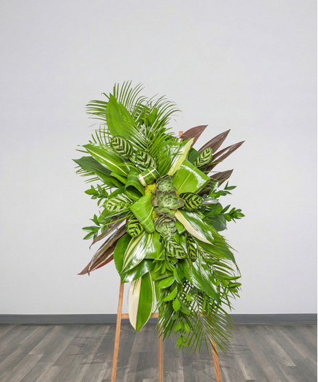 Green standing spray funeral arrangement with layered tropical foliage and succulents from Billy Heroman’s Florist in Baton Rouge