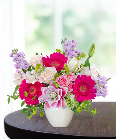 Pink Carats floral arrangement featuring pink roses, gerbera daisies, lilies, hydrangeas, and spring blooms in an ivory vase – an April birthday exclusive.