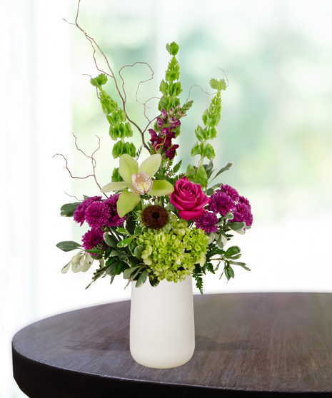 Green and purple birthday flower arrangement with orchids, roses, and hydrangeas