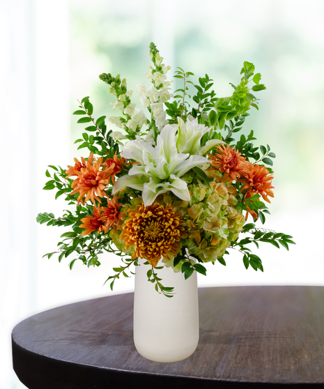 Topaz to Remember November birthday flower arrangement with white lilies, white roses, orange mums, and green Bells of Ireland in a white vase