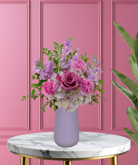 Pretty in Purple exclusive Valentine's and February birthday flower arrangement with lavender roses, white lilies, purple stock, and magenta mums in a frosted lavender vase.
