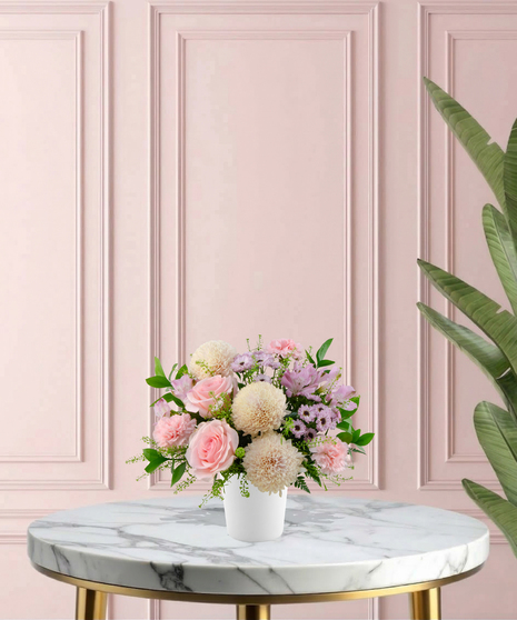 Sweetest Mum Mother's Day flower arrangement featuring light pink roses, ivory cremones, lavender daisies, and pink carnations in a matte white ceramic vase.