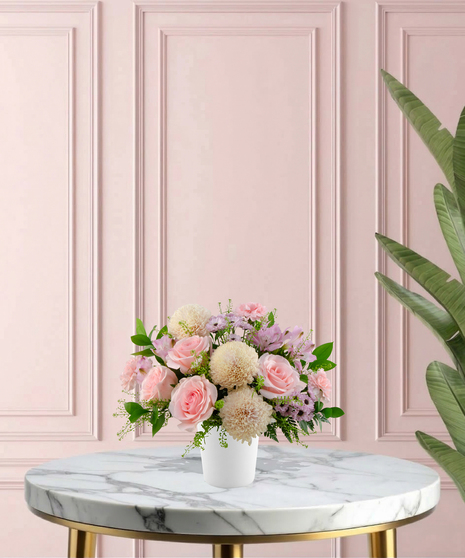 Sweetest Mum Mother's Day flower arrangement featuring light pink roses, ivory cremones, lavender daisies, and pink carnations in a matte white ceramic vase.