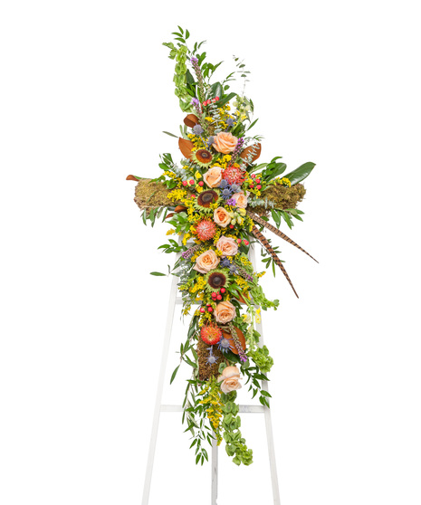 The Great Outdoors Cross Stand with peach roses, pincushion protea, moss, berries, and feathers on a white easel